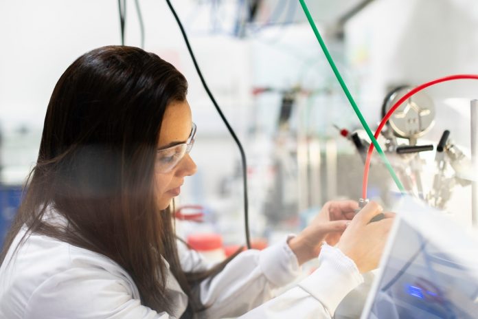 Mulher em laboratório de inovação com óculos de proteção e jaleco