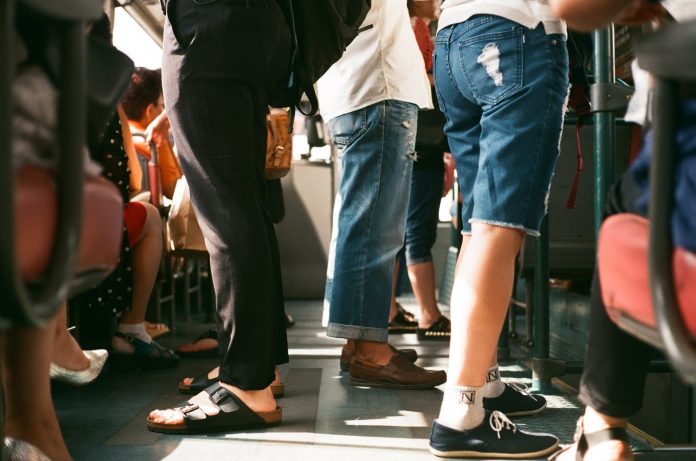 Fotografia de passageiros no ônibus. É possível visualizar apenas a cintura e pés dos passageiros.