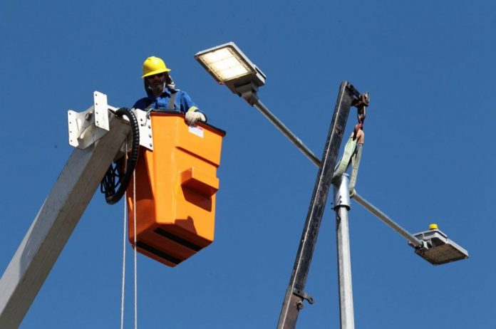 Fotografia de profissional trabalhando na rede de iluminação pública em licitação