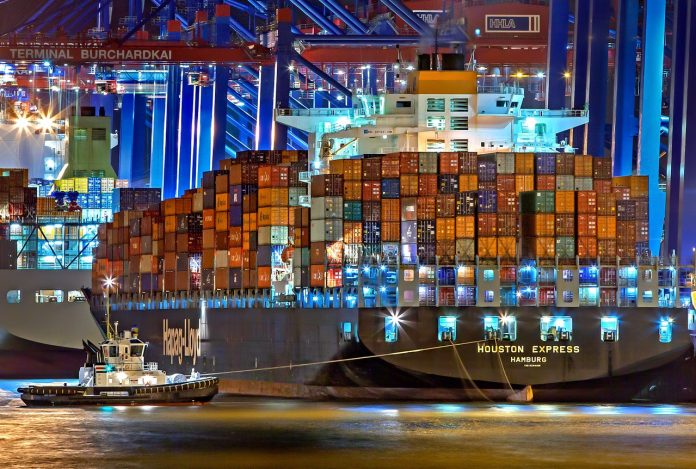 Fotografia de navio sendo rebocado por pequena embarcação